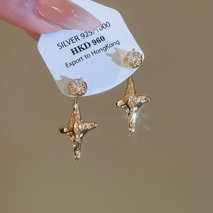 Macro shot of gold star earrings with sparkling zircon inlay and 925 silver tag