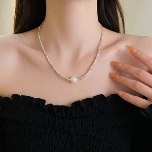Minimalist pearl necklace with faceted silver beads worn by model for elegant style