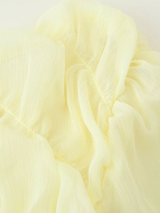 Detailed macro view of the light yellow pleated chiffon fabric texture and soft material