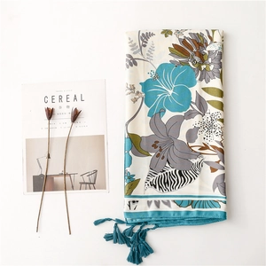 Detail of floral printed summer shawl with vibrant teal tassels and bohemian leaf patterns