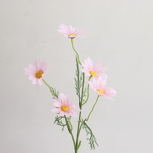 Macro detail of artificial pink daisies with yellow centers and realistic green leaves