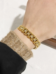 Detail of 18K gold-plated watchband style bracelet with inlaid white sparkling crystals