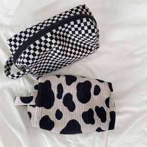 Detailed top view of textured checkered and cow print cosmetic bags with handles