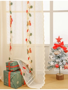 Detail of Christmas lace curtain with bell embroidery and festive warm indoor atmosphere