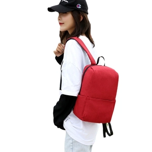 Minimalist red canvas backpack for travel and students, shown on model with front pocket