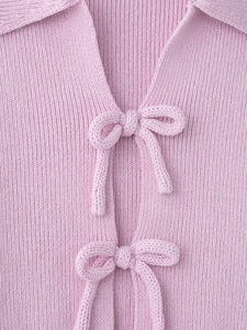 Detail of pink ribbed knit top featuring delicate bow tie closures and a turn-down collar