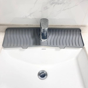 Grey silicone faucet splash guard with wavy texture shown on a white kitchen sink