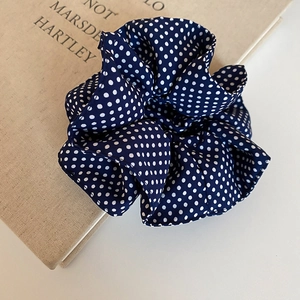 Detailed macro view of dark blue polka dot fabric scrunchie with layered texture