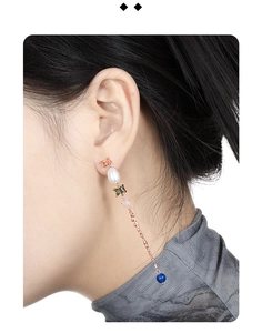 Detail of rose gold tassel earrings with colorful baroque pearls and gemstones on model