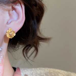 Detailed view of 24K gold plated flower earring showing metallic texture on model