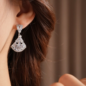 Close-up of fan-shaped silver earrings with sparkling cubic zirconia on model
