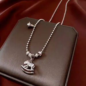Collier avec pendentif cheval à bascule en argent et zircons sur boîte à bijoux