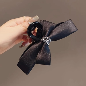 Close-up of black satin bow hair claw clip with shimmering rhinestone center piece
