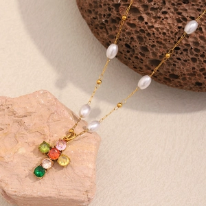 Détail d'un collier croix plaqué or 18K avec zircons colorés et perles sur pierres