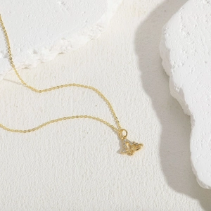 Macro shot of gold butterfly pendant with sparkling cubic zirconia on a stone surface