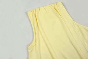 Detail of yellow one-shoulder dress showing smooth fabric texture and reinforced stitching
