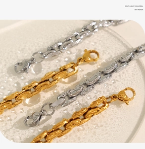 Detail of gold and silver cuban link chains with lobster clasps on frosted glass