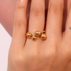Detailed close-up of a 18K gold plated ring with four unique spherical beads on a hand