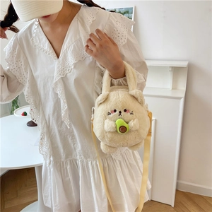 Cute beige cat plush crossbody bag with avocado detail shown on a model in white dress