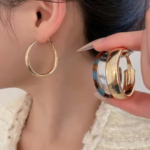 Polished gold hoop earrings and tortoiseshell acrylic hoops worn by a model