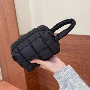 Close-up of black quilted cosmetic bag with gold zipper and puffy nylon texture