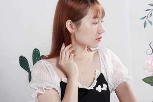 Gros plan de longues boucles d'oreilles dorées en forme de visage portées par modèle