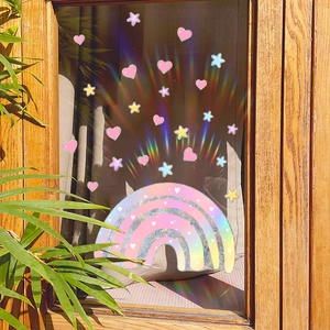 Rainbow prism window decals with hearts and stars casting colorful light on curtains