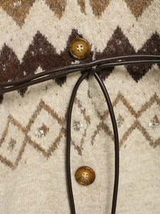 Close-up of knit cardigan showing jacquard patterns, silver bead embroidery and amber buttons