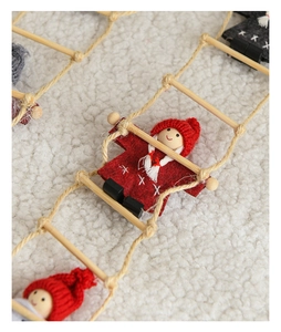 Close-up of felt Santa on a wooden rope ladder against a white fleece background