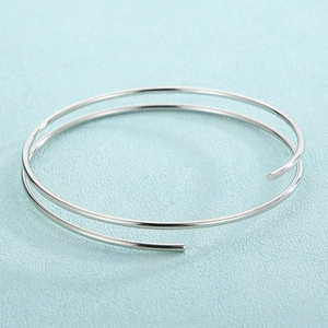 Detail of a minimalist polished silver stainless steel double-layered spiral open bangle