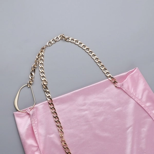 Détail d'une robe en satin rose avec bandoulière chaîne dorée et anneau géométrique
