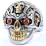 Detail of gothic skull ring with gold accents and red crystal eyes in silver finish