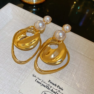 Macro detail of golden irregular circular pearl earrings with polished metallic finish