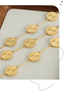 Macro detail of gold plated round sunburst pendants with radial texture on a chain