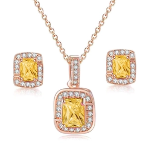 Detail of rose gold jewelry set with emerald-cut yellow gemstones and halo diamonds