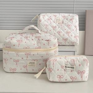 Three-piece quilted makeup bag set with pink floral and bow patterns in various sizes