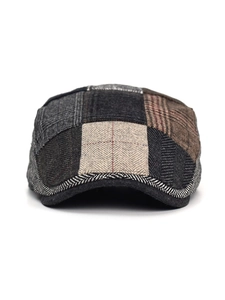 Detail of multi-color patchwork flat cap showing tweed texture and brim craftsmanship