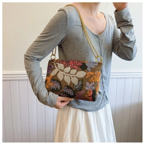 Close-up of colorful floral embroidery on a brown evening clutch with a gold chain