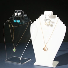 Clear and white acrylic jewelry stands for necklace and earring display on black background