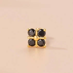 Macro shot of gold cross stud earring with four black round zircon inlays on pink background