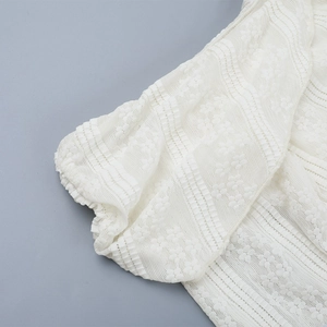 Detailed macro view of white lace floral patterns and elastic cuffs on a long sleeve dress