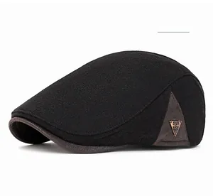 Detail of black twill flat cap featuring a brown leather brim and metal logo accent