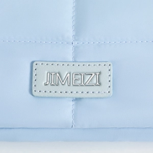 Close-up of light blue quilted fabric laptop sleeve with JIMEIZI metal brand logo plate