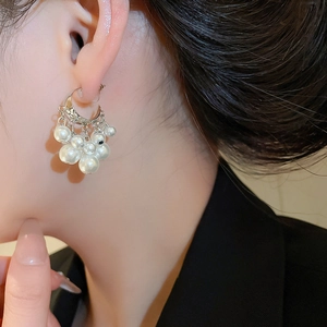 Close-up of elegant C-shaped beaded tassel earrings with white pearls on a model