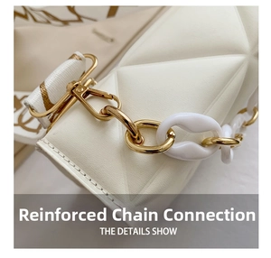 Detail view of the reinforced golden chain links and resin strap on a white quilted bag