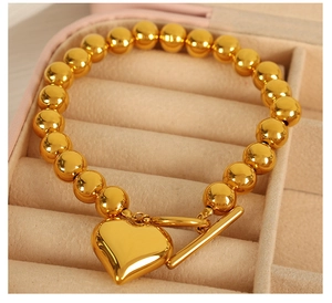 Close-up of golden beaded heart bracelet with T-bar clasp in a pink jewelry gift box