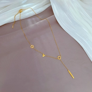 Macro shot of gold LOVE letter necklace with pendant on elegant white silk background