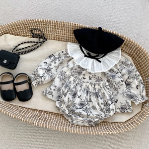 Close-up of baby floral cotton set with ruffled collar, black bows, and matching beret