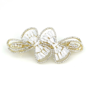 Elegant gold bow hair clip with sparkling white zircons and crystals on white background