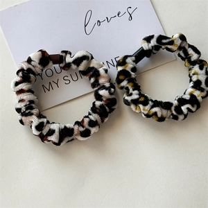 Detail view of two leopard print velvet scrunchies with soft texture on a white background